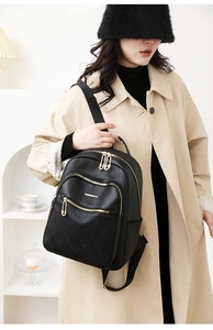 Detail of black leather backpack featuring floral embossing and golden zippers on premium PU