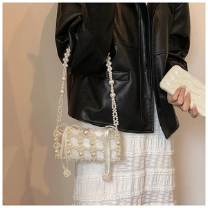 Detail of woven faux pearl handbag with satin inner lining and ribbon bow ornament