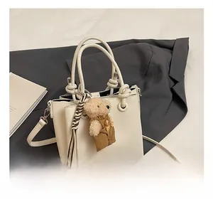 Detail van gebroken witte bucket bag met lychee textuur en schattige pluche beer hanger