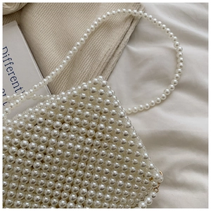 Detailed macro view of handmade white pearl woven bag with golden metal buckle clasp