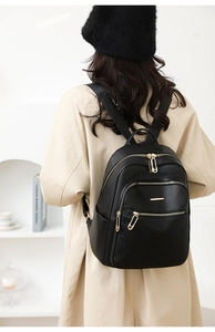 Close-up of black leather backpack with floral embossing and gold paperclip zippers