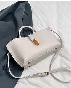 Macro shot of off-white lychee pattern leather bucket bag with brass buckle detail