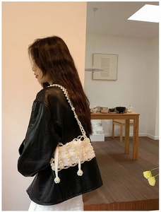Detail view of pearl beaded mini bag with satin bow on black leather jacket