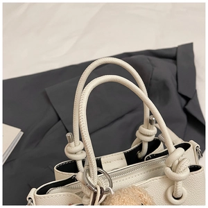 Detail of white lychee texture bucket bag with rope handles and cute bear charm