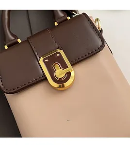 Détail de la boucle dorée vintage et des coutures en cuir texturé sur un petit sac bandoulière