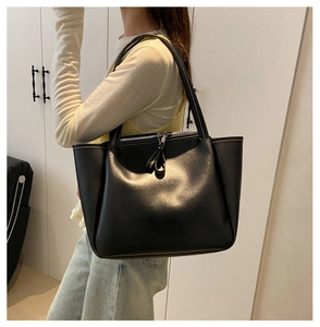 Macro detail of black leather tote bag featuring white contrast stitching and top zipper