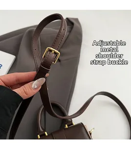 Détail de la bandoulière réglable avec boucles en métal doré sur le sac en cuir brun