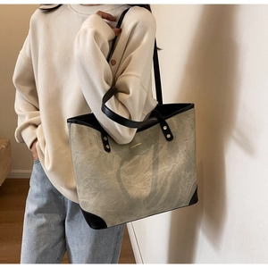Detail of grey canvas tote bag with black leather handles and marble wash texture