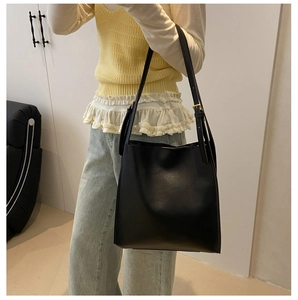Detailed view of the matte black tote bag with gold hardware and slim adjustable straps