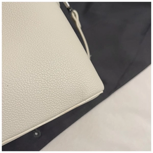 Macro shot of off-white lychee texture leather bucket bag with detailed edge stitching
