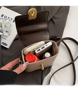 Détail de l'intérieur du sac vintage montrant le rangement pour téléphone et maquillage