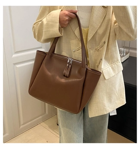 Detailed view of dark brown leather tote bag with silver double zipper and slim handle
