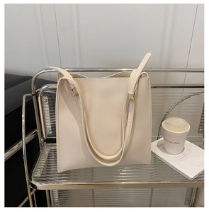 Close-up of the smooth cream leather texture and metal strap buckle on the tote bag
