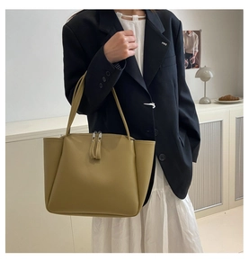 Olive green leather tote bag with long shoulder straps shown in a modern interior setting