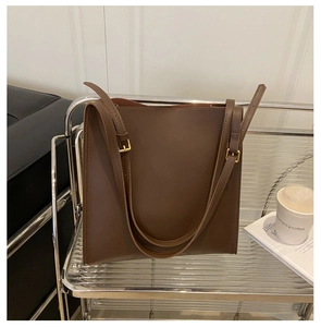 Detailed view of brown leather tote bag with adjustable straps and gold buckles