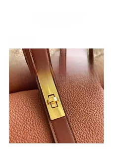 Detail of a golden metal swivel lock on a caramel lychee pattern leather handbag