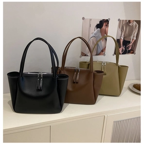 Close-up of minimalist tote bags with fringe zipper detail in black, brown and olive green