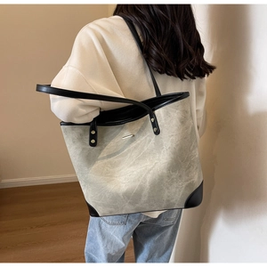 Detail view of large grey canvas tote bag with black leather trim and long straps