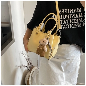 Detail of yellow lychee leather bucket bag with knot handle and teddy bear charm