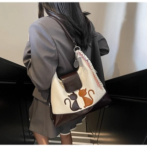 Detail of contrast color tote bag with cat embroidery and silk scarf on modern stairs