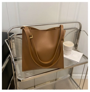 Detail of a brown leather tote bag with gold hardware placed on a silver metal cart