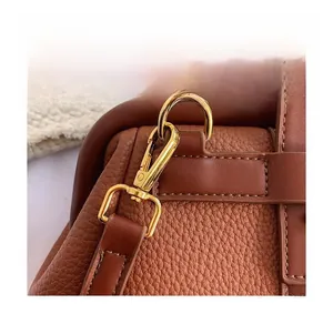 Detail of dark brown lychee leather texture and premium gold metal shoulder strap buckle