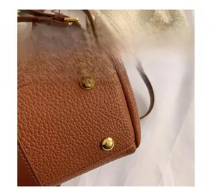 Close-up of golden metal rivets on the bottom of a brown lychee pattern leather bag