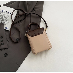 Vue détaillée du sac carré bicolore montrant la base stable avec quatre clous de protection dorés