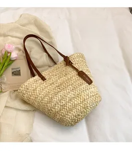 Détail du cabas en paille beige avec anses en cuir marron et étiquette décorative