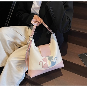 Detail view of the pink flap with a cartoon cat pattern and the adjustable shoulder strap