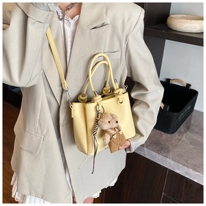 Close-up of yellow bucket bag with lychee texture and cute bear charm detail