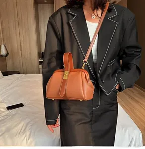Detail of a brown lychee pattern leather doctor bag with gold metal clasp on a model
