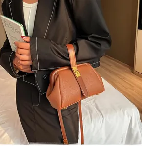 Brown lychee leather doctor bag with a gold square lock shown in a lifestyle model shot