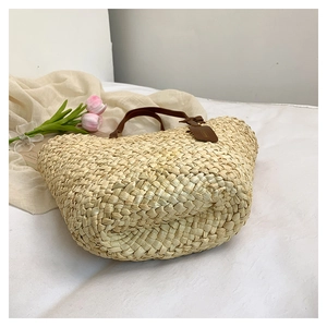 Détail d'un sac de plage en paille tissé à la main avec poignées en cuir brun