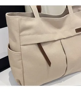 Detail of a khaki canvas tote bag featuring multiple pockets and durable thick fabric texture