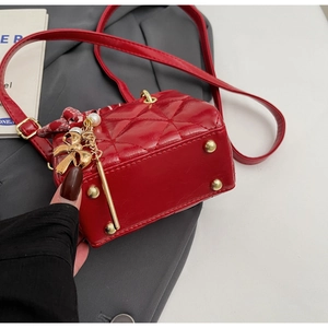 Detail of red quilted square handbag with gold protective studs and bow pearl charm