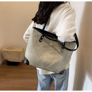 Detail showing marble texture gray tote bag with black leather stitching and metal trim