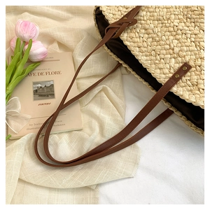 Détail du sac en paille tissée avec lanières en cuir marron et rivets en métal