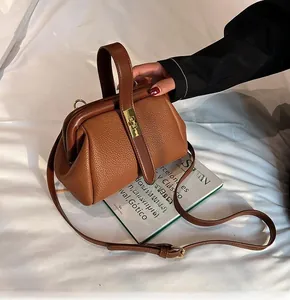 Detail of vintage brown pebble leather handbag with gold metal clasp and sturdy handle