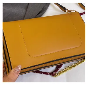 Dettaglio della borsa a tracolla giallo zenzero con texture liscia e catena dorata