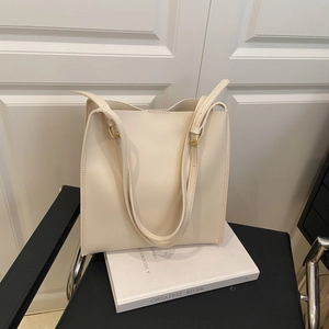 Minimalist creamy white leather tote bag with dual shoulder straps and gold buckles