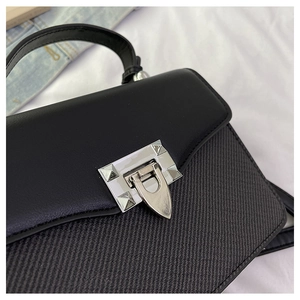 Detail of color-block handbag showing twill fabric texture and metallic pyramid stud lock