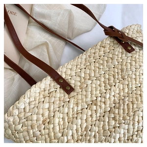 Gros plan d'un sac cabas en paille tissée avec texture chevrons et bandoulière en cuir