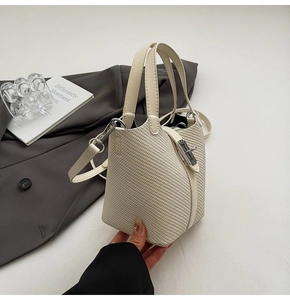 Detail der cremefarbenen geflochtenen Eimertasche mit silbernem Verschluss und Gurt