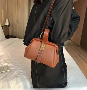 Detail view of brown lychee grain leather doctor bag with a gold metal clasp and top handle