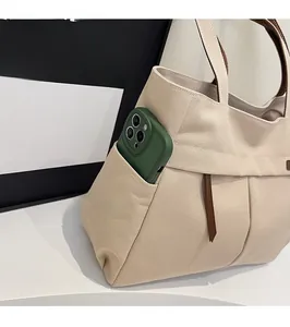 Close-up of canvas tote side pocket showing functional storage for a green smartphone