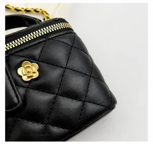 Detail of black quilted leather box bag with gold flower clasp and chain strap