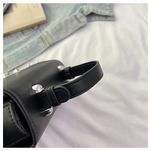 Detailed close-up of textured leather stitching and silver buckles on a handbag