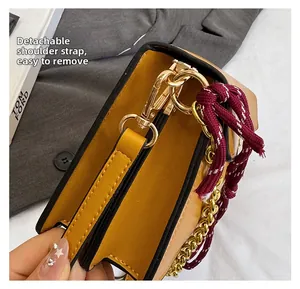 Dettaglio borsa pelle gialla con hardware dorato, catena e gancio a tracolla rimovibile