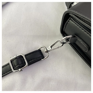 Detailed view of silver lobster clasp and adjustable buckle on black leather handbag strap
